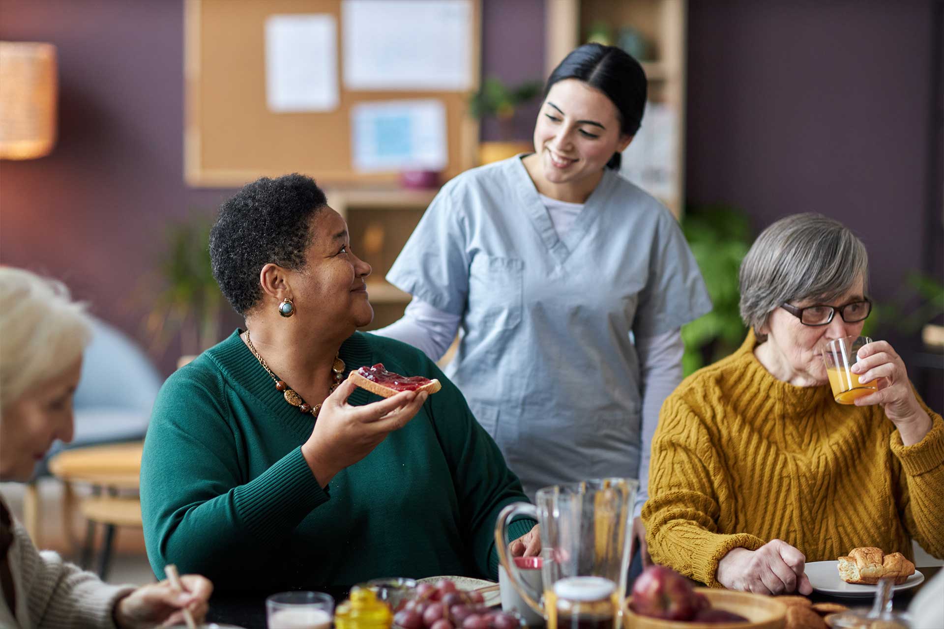 young-nurse-assisting-senior-people-during-breakfa-V26QWH7